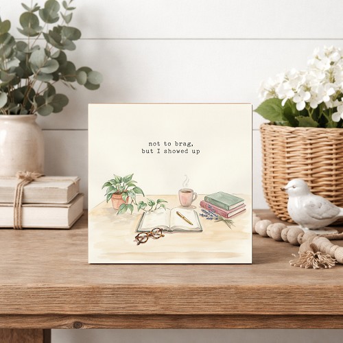 Not to Brag But I Showed Up funny sign with watercolor books, coffee, journal, glasses and green houseplants 