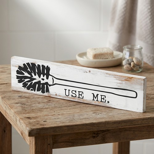 Funny Use Me toilet brush bathroom sign with black toilet brush design on rustic whitewashed background 